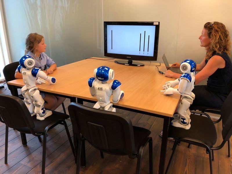 Wenn Roboter Märchen erzählen:

Können auch Roboter Gruppendruck ausüben? Das wurde in einer Studie mit drei Robotern vom Typ Nao und einer Gruppe Erwachsene und einer Geuppe Kindern untersucht. Die Humanoiden können sprechen und gestikulieren und sind deutlich kleiner als Erwachsene (etwa 60 Zentimeter). Die Versuchspersonen mussten die Länge von drei Strichen miteinander vergleichen – die Roboter behaupteten dann fälsdchlicherweise, dass ein anderer Strich länger sei. Kinder geben dem sozialen Druck nach, den die Gruppe von Robotern ausübt. Erwachsene hingegen halten dieser Beeinflussung stand, obwohl sie sich in der gleichen Situation von anderen Menschen beeinflussen lassen würden.
 (Tony Belpaeme/Ghent University)