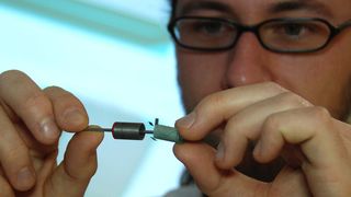 Die Professur Elektrische Energiewandlungssysteme und Antriebe der TU Chemnitz erforscht die Fertigung von Motoren für Elektrofahrzeuge im Siebdruckverfahren. Mathias Lindner von der Professur Elektrische Energiewandlungssysteme und Antriebe montiert die gedruckte Folienwicklung in den Rotor eines kleinen Motors. (TU Chemnitz/Mario Steinebach)