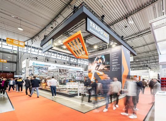 Auf der Stuttgarter Logimat lieferte ein AMR mit Moveli-Aufsatz eine Palette mit Kartons dem Trapo Cobot Palletizer an, der ohne Zaun palettieren und depalettieren kann. Den Gästen reichte der Cobot einen XXL-Thermobecher als Gruß.(Bild:  Trapo)