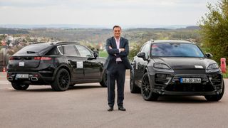 Michael Steiner, Mitglied des Vorstandes Forschung und Entwicklung bei Porsche, vor zwei getarnten Prototypen des E-Macan im letzten Jahr. (Porsche)