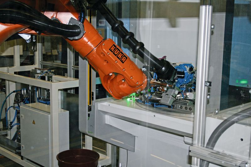 In einem ersten Bearbeitungsschritt werden die Platinen auf die Aufnahme eines Laserrundschalttischs aufgelegt. Dort wird simultan auf beiden Platinen der Schriftzug des Auto­mobil­herstellers mittels Laser eingeschnitten. (Kuka)