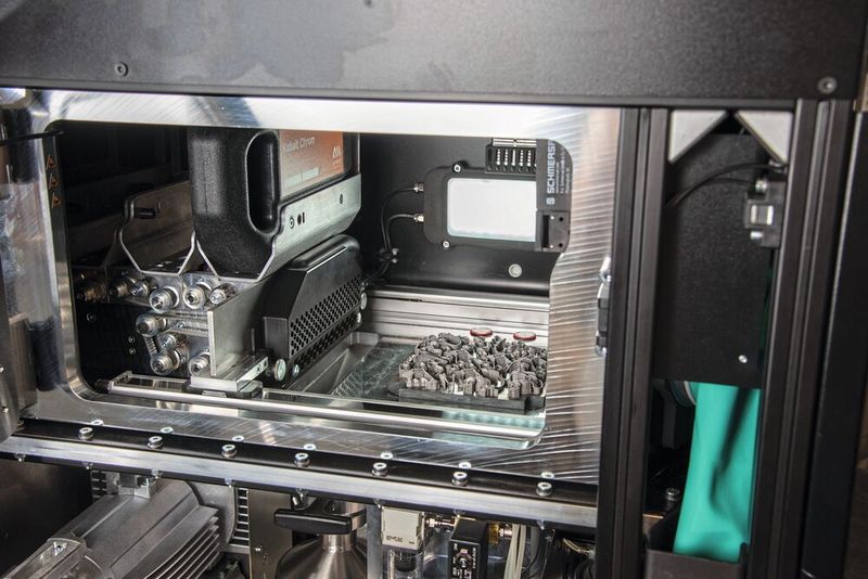 Links im Druckraum die Beschichtereinheit mit Pulverkartuschen. (Bild: A-Metal AG)