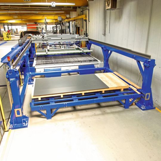Ein Vakuum-Saugheber transportiert Blechplatinen und geschnittene Blechteile zum und vom Wechseltisch weg. Ein Vakuum-Saugheber transportiert Blechplatinen und geschnittene Blechteile zum und vom Wechseltisch weg.