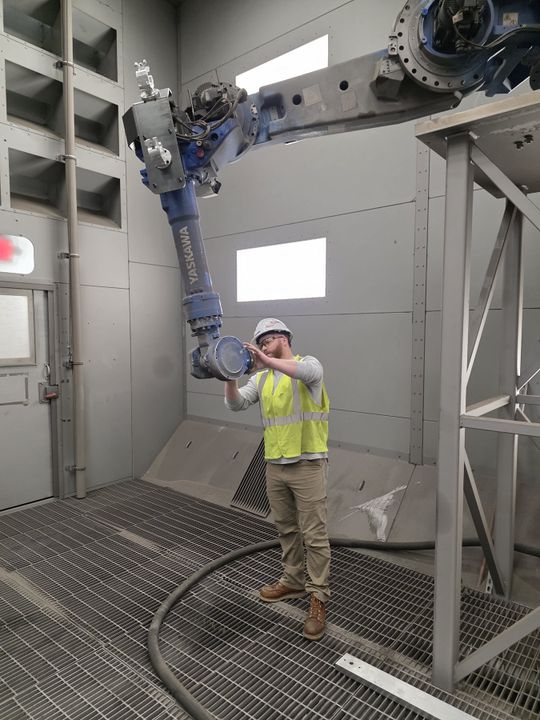 Korey Greene untersucht einen Strahlroboter, der in der automatisierten Containerproduktion eingesetzt wird. „Hier bei Sea Box hat man viele Aufgaben, und das ist wirklich lohnenswert“, sagt er.(Bild:  Sea Box)