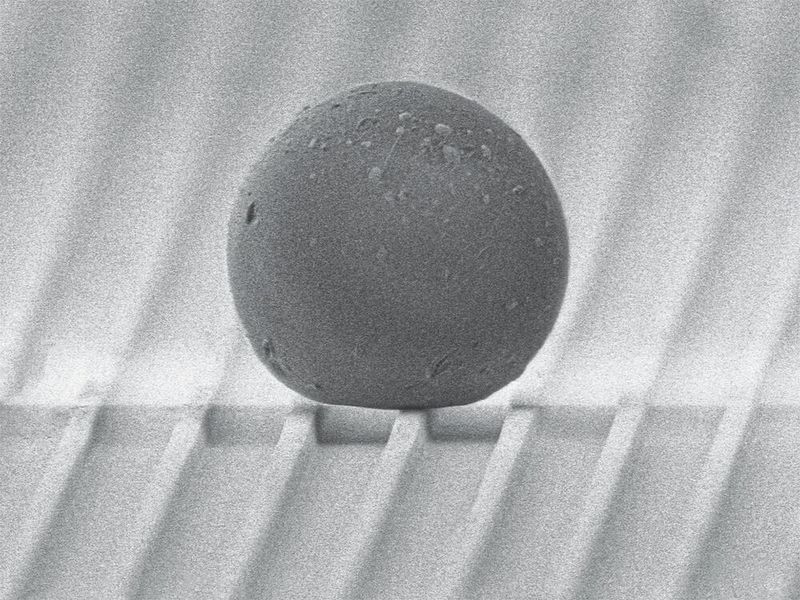 Testobjekt Polystyrol-​Kügelchen auf der  gerillten Oberfläche.  (Bild: Julian Schmid / ETH Zürich)