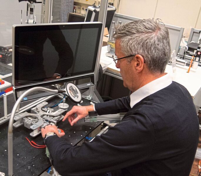 LaFT-Leiter Jens P. Wulfsberg demonstriert an einer Vorschubeinheit für Mini-2D-Werkzeugmaschinen, wie Armstütze aus dem 3D-Drucker den Monteur bei der Arbeit unterstützen.  (Nikolaus Fecht/VdW)