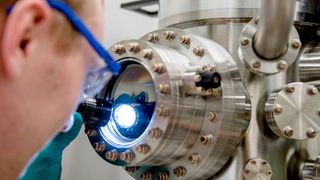 Michael Meischein vor dem Sputter-System, in dem die Nanopartikel durch simultane Beschichtung aus mehreren Quellen in einer ionischen Flüssigkeit erzeugt werden. (RUB, Marquard)
