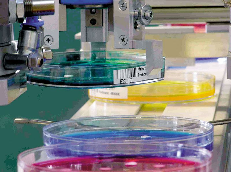 Abb.4: Ein Greifer verbindet Mirob mit einem Förderband. Es können so bis zu hundert Proben pro Stunde vorbereitet werden, ohne dass der Mensch eingreifen muss. 
Der Barcode gewährleistet die eindeutige Zuordnung der Proben und eine Rückverfolgung. Dokumentiert werden dazu die Vorgaben für die Bildverarbeitung, das Übersichtsbild der Kamera mit Barcode und den Entnahmepositionen und weitere Prozessparameter wie Ablageposition oder Datum.
 (Archiv: Vogel Business Media)