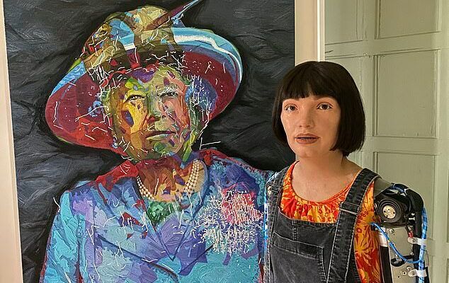 Die Roboterkünstlerin Ai-Da vor ihrem jüngsten Werk: Dem stilisierten Gesicht von Queen Elizabeth II., das zum 70-Jahres-Jubiläum der Thronbesteigung auf Leinwand gebannt wurde. Die Art der Malerei übrigens hat einen Hintergrund...