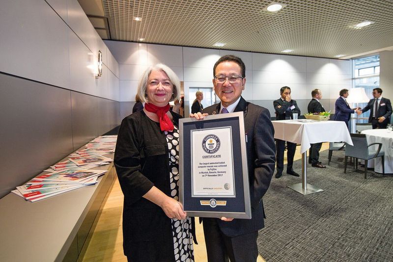 Andrea Clatworthy und Tatsuya Tanaka mit dem Guiness-Zertifikat für das größte animierte Tablet-Mosaik der Welt.   (Fujitsu)