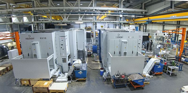 Gesamtansicht der flexiblen Fertigungszelle: Zwei REIDEN RX18, im Hintergrund ist das Palettenlager. Die beiden Rüstplätze sind rechts angeordnet. Die im Bild links befindliche erste REIDEN RX18 ist mit einem direkt getriebenen Rundtisch ausgestattet wie auch für Drehteile bis über 3000 mm Durchmesser ausgelegt, die über das Dach beladen werden können. (Bild: Matthias Böhm)