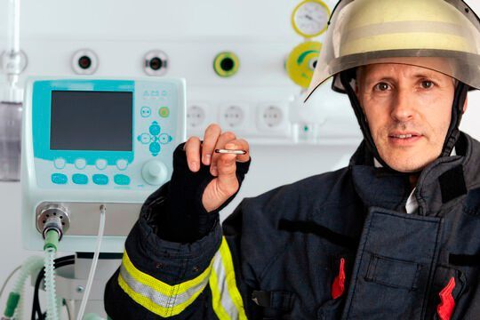 Der kleinste Feuerlöscher der Welt in den Händen eines Feuerwehrmannes vor einem Beatmungsgerät Der kleinste Feuerlöscher der Welt in den Händen eines Feuerwehrmannes vor einem Beatmungsgerät