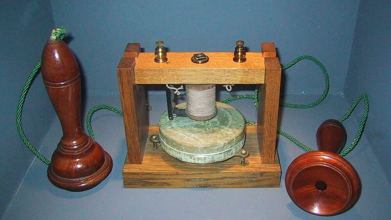Telefon: Modell des ersten Telefonapparates, der 1875 von Alexander Graham Bell entwickelt wurde, in der historischen Sammlung des Museums für Telekommunikation in Pleumeur-Bodou, Frankreich. Die Apparaturen auf beiden Seiten sind Modelle des später von Bell erfundenen Empfängers (Kopfhörer).