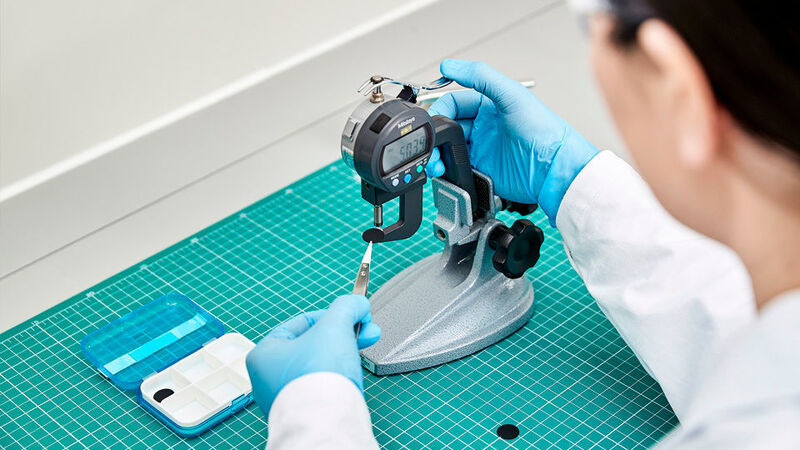 Eine Labormitarbeiterin misst die Dicke einer Elektrode nach deren Verdichtung. Die Verdichtung dient dazu, die Elektrode mechanisch zu stabilisieren, zu homogenisieren und den Energiegehalt zu erhöhen. (BASF)