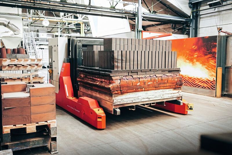 Three driverless transport vehicles were developed for the transport between the presses and tunnel kiln at RHI Magnesita. The heavy transport achieves a total weight of 26 tons and is in operation 24/7. (Image:EK Robotics)