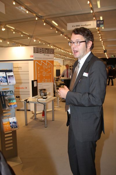 Wolfgang Marquardt, Fachbereichsleiter it´s OWL Clustermanagement, stellt den Gemeinschaftsstand vom Spitzencluster it´s OWL vor. Die Mitglieder beschäftigen sich mit der Frage wie Intelligenz in die Maschine kommt. (Finus)