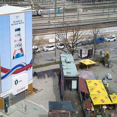 Der Vertical-Parking-Turm in der Nähe des Münchener Ostbahnhofs ist mit Holzelementen verkleidet. Ein Teil der Flächen wird für Werbebanner verwendet, andere wurden künstlerisch gestaltet (Entwurf von Mariella Kerscher).  (Bild: Vepa Vertical Parking )