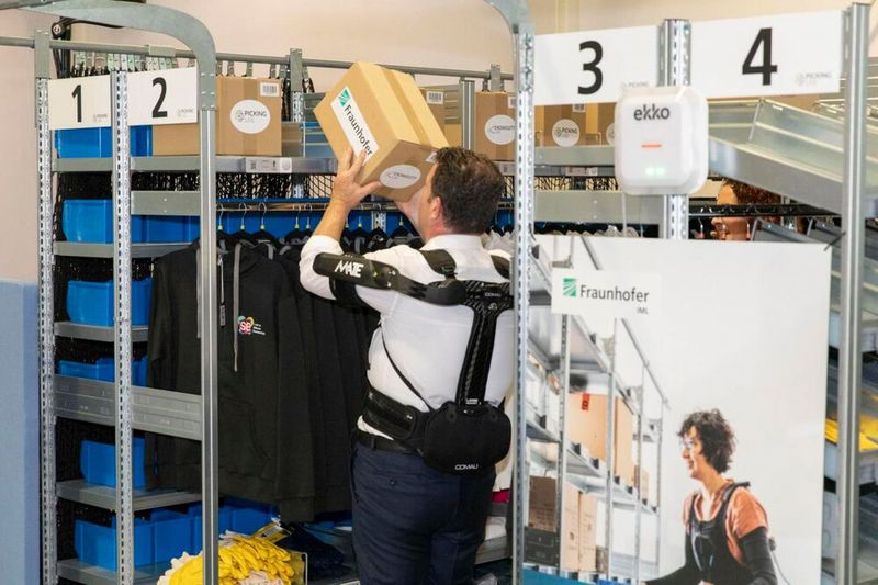 Bundesarbeitsminister Hubert Heil bei der Arbeit! Hier lernt er in der Praxis kennen, wie ein Exoskelett, bei schwerer körperlicher Arbeit hilft. (Bild: FRaunhofer IML)