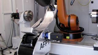 Automatische Fertigung von Druckbehältern: Das Anlagenkonzept basiert auf einem Sechs-Achs-Knickarmroboter, einem kompakten Tapelegekopf und einem sogenannten Tumble-Winder, der den zu bewickelnden Grundkörper (Liner) aufnimmt. Das Zusammenwirken von Roboter und Tumble-Winder führt zur Optimierung der Bahnbewegungen.  (Bild: AFPT)