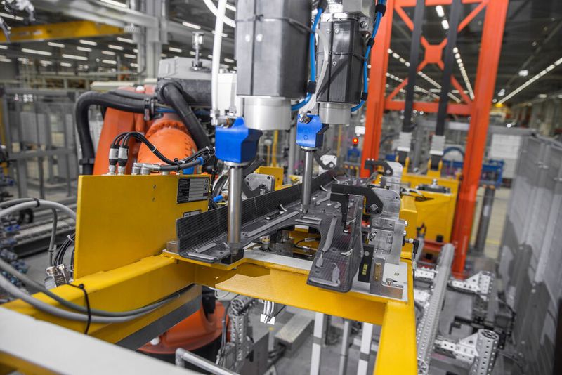 Nichts wird beim Kleben des CFK-Trägertunnels des 7er-BMW dem Zufall überlassen: Die Dosierung und der Kleberauftrag erfolgen positionsgenau per Roboter. Das Bauteil wird dann auf eine Stahlkomponente aufgeklebt. (BMW)