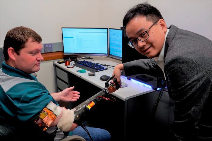 University of Minnesota Department of Biomedical Engineering Associate Professor Zhi Yang shakes hands with research participant Cameron Slavens, who tested out the researchers' robotic arm system. (Neuroelectronics Lab, University of Minnesota)