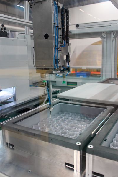 Der Roboterarm legt spritzgegossene Kunststoffdeckel möglichst platzsparend in einem Transportbehälter ab.  (Rodinger Kunststoff-Technik GmbH)