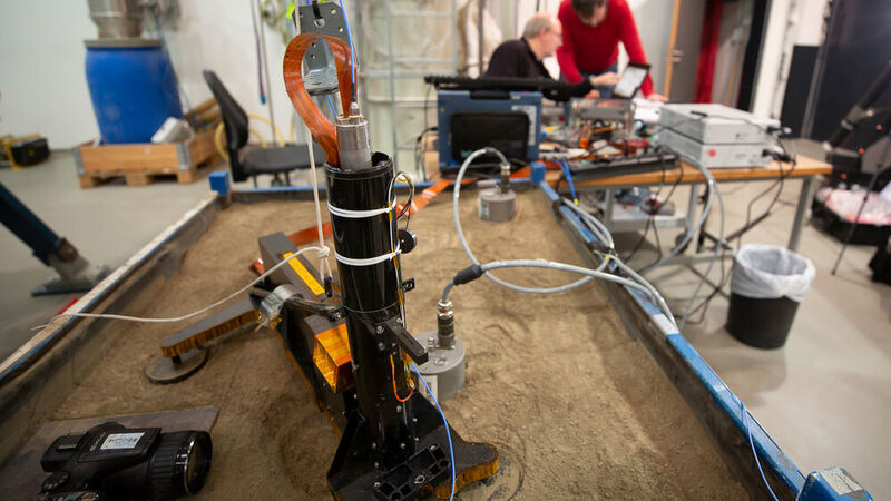 Das HP3-Experiment steht auf einer mit Sand gefüllten Box. Oben am Gehäuse ist ein Stück des Maulwurfs zu erkennen, der sich mit einem Schlagmechanismus allein in den Untergrund hämmern kann. (Testaufbau des HP3-Experiments am DLR in Bremen / CC BY 3.0)