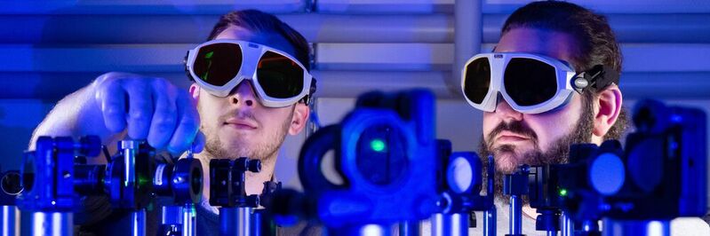 Die Doktoranden Paul Herrmann (l.) und Sebastian Klimmer experimentieren an einem Laser-Versuchsaufbau an der Universität Jena. Dank 2D-Materialien fließen Informationen bis zu 1.000-mal schneller als mit Strom.