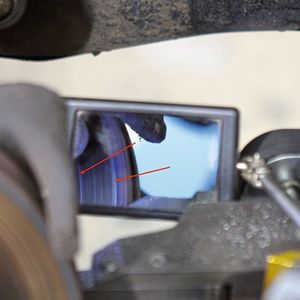 Für die Innenseite empfiehlt sich ein Spiegel. Auch hier lässt mal idealerweise an drei Stellen (innen, Mitte, außen) der Reibfläche den Meißel ganz leicht „zupfen“ (siehe Pfeile) und ermittelt so die dünnste Stelle der Scheibe, die dann als Nullmaß dient.(Bild:  Dominsky/»kfz-betrieb«)