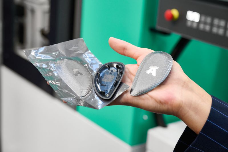 El acabado de alta calidad de la carcasa de la llave a distancia, fabricada con PC/ABS reciclado, se consigue mediante la técnica de laminado IMD y el uso de moldes texturizados. La pieza moldeada por inyección, troquelada en forma rectangular junto con la lámina, se fresa en una estación posterior para darle el contorno final adecuado.(Bild:  Arburg)
