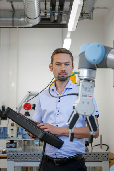 Stefan Trabesinger, Mitarbeiter am Institut für Fertigungstechnik der TU Graz, arbeitet mit einem kollaborativen Roboter in der Fabrik. (Lunghammer / TU Graz)
