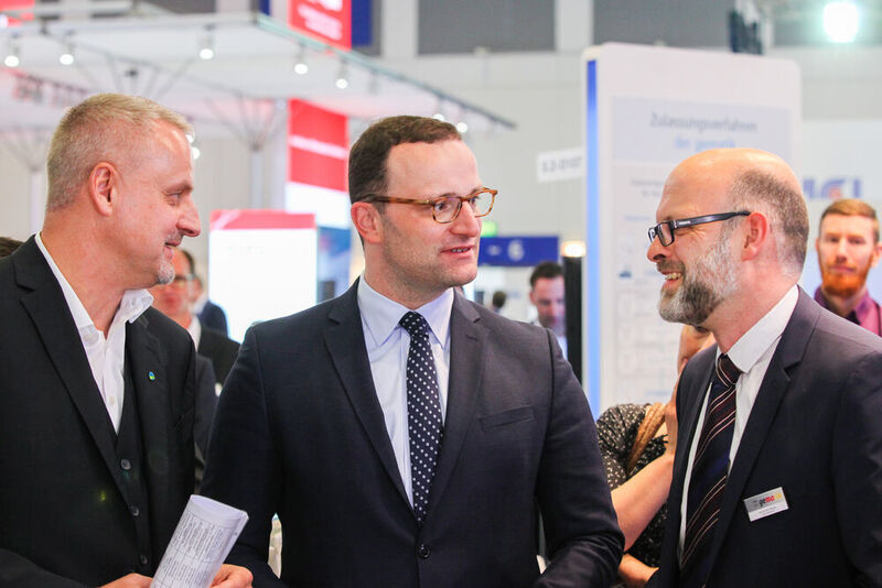 Jens Naumann (Vorstandsvorsitzender des Bundesverbands Gesundheits-IT (bvitg) (l.), und Jens Spahn, Bundesgesundheitsminister (m.), am Stand der gematik (Messe Berlin GmbH)