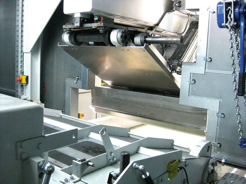 Blick aus der Schallschutzkabine der Mühle: Gut zu sehen ist hier die breite Frontplatte der Schiebersektion des Getecha-Manipulators, der in seiner Parkposition bis direkt vor die Einzugswalzen der Mühle fährt.  (Stöcker)