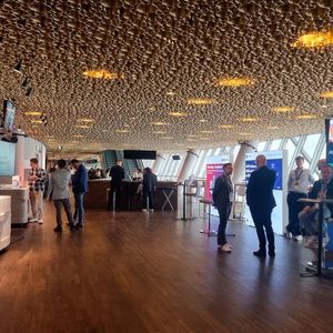 Auf der vierten Ebene befand sich die Business Lounge. Dort bot die Veranstaltung eine große Mainstage, einen kleinen Messebereich mit vier Ausstellern, eine Speaker Lounge und eine Buffet-Ecke. Auf der Mainstage startete die Begrüßungsrede mit anschließender Keynote.(Bild:  © Serina Sonsalla)