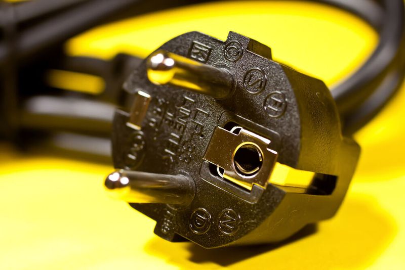 Schon Werner von Siemens schlug vor, ein dreipoliges Schutzkontaktsteckersystem zu verwenden, um tödliche Stromschläge durch unter Strom stehende Gehäuseteile zu vermeiden. Der Schuko-Stecker, wie er heute millionenfach in Geräten verbaut ist, geht auf  eine 1929 patentierte Erfindung von Wilhelm Klement, Oberingenieur der Siemens-Schuckertwerke, zurück. Dabei sind die metallischen Gehäuseteile über den grün-gelben Schutzleiter des Gerätekabels mit den beiden seitlich am Stecker befindlichen Schutzkontakten verbunden. Beim Einstecken des Steckers in die Dose wird zuerst eine Verbindung zwischen den Schutzkontakten und „Erde“ und danach mit den stromführenden Kontakten hergestellt. Steht das Gehäuse durch einen Defekt unter Strom, so spricht der FI-Schalter oder die Sicherung an. (Power plug / Gerwin Sturm / CC BY-SA 2.0)