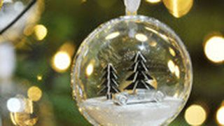 Die exklusiven Audi-Christbaumkugeln beinhalten eine Miniatur-Winterlandschaft aus Aluminium: zwei kleine Tannenbäume und ein Auto Union Typ C von 1936. (Foto: Audi)