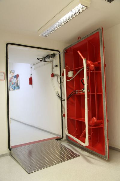 Die Schleusentür: Wer Zutritt zum Bunker erlangen wollte, hätte durch eine Schleuse gemusst. In dieser wäre die Person per Geigerzähler auf Strahlung untersucht worden. Für die Person, die die Grenzwerte überschritten hätte, gab es seitlich vom Eingang im Schleusenbereich eine Dusche. Nach dem Abbrausen hätte es eine zweite Untersuchung gegeben. Das Prozedere wäre von einem Wachmann in einem gesonderten Raum mit Panzerglasverglasung kontrolliert worden. Wäre die Person auch nach der Dusche mit für weitere Personen gefährlicher Strahlung vesehen gewesen, wäre der Zutritt versagt und die Person unter Umständen eleminiert worden.  (Bild: Comback)