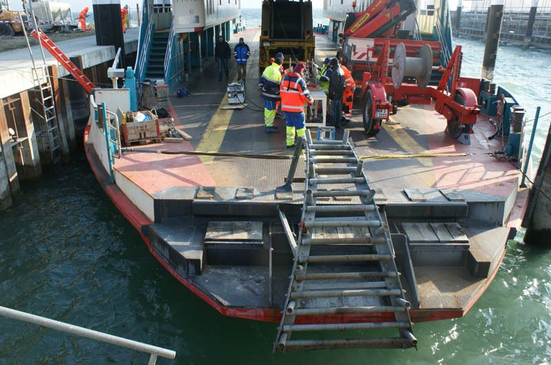 Heute geht es nur per Leiter an Deck. Die Männer, die die Kabel verlegen sollen, nehmen die Mechanik des Provisoriums in Augenschein. Es besteht aus einem Tisch und einer Führung für das Kabel.  (Archiv: Vogel Business Media)