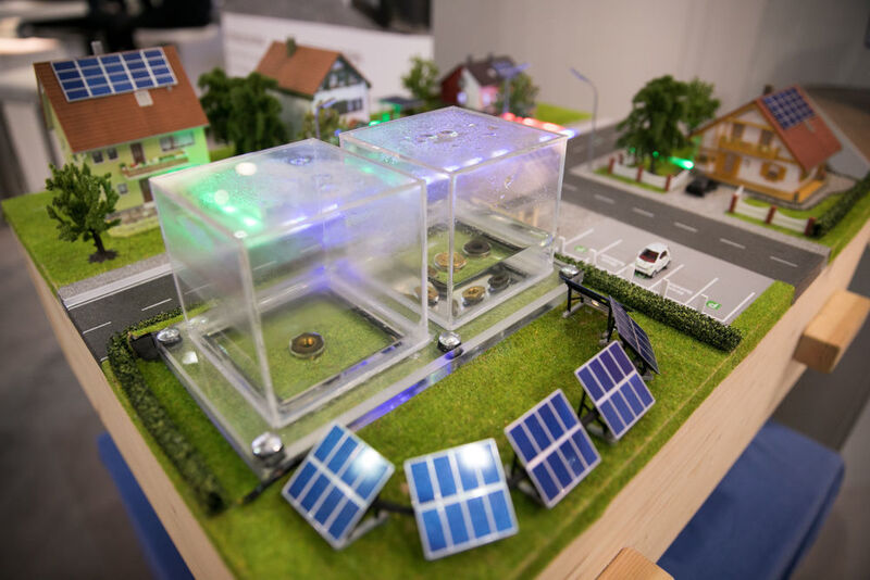 Hier wird ein Smart Grid als Modell gezeigt. Der Energiefluss wird mit grünem Licht dargestellt. Die beiden Plexiglasboxen in der Mitte stellen exemplarisch einen Kurzzeit- und einen Langzeitenergiespeicher dar. (Michael Heck)