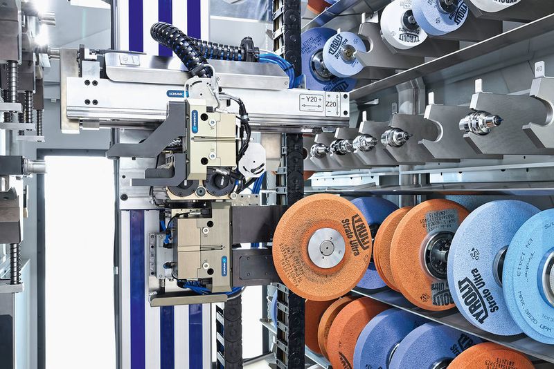 Sobald die Schleifscheibe aus dem rechten Regalsystem entnommen ist, schwenkt der Greifer um 180°, um die Schleifscheibe mit dem entsprechenden Kühlmittelschutz im linken Regalsystem zu kombinieren.  (Schunk)
