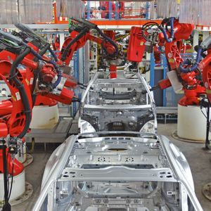 Beim Anbringen und Befestigen von Karosserieteilen bilden Roboter ein Spalier. Sie stehen in dichten Reihen nebeneinander und schweißen, nieten, falzen, bringen Bolzen und manches mehr – teilweise in parallel laufenden Prozessen.