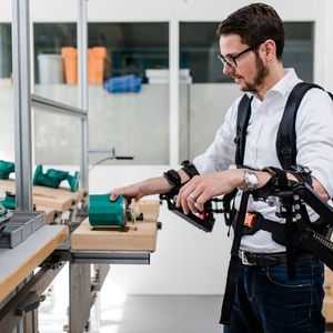 Moritz Hämmerle, Leiter Competence Team Production Excellence am Fraunhofer IAO, testet das Exoskelett in der Modellfabrik.