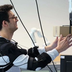 Forscher Federico Masiero nimmt ein Päckchen von einem Neura-Cobot entgegen.(Bild:  Andreas Schmitz / TUM)