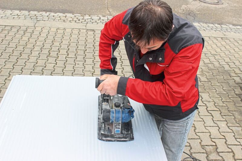 Der Inhaber des Hallenbauunternehmens Lienerth GmbH, Georg Lienerth, beim Test des „Panel Cutter Trutool TPC 165“ von Trumpf. Markierungen an dessen Rahmenkonstruktion erleichtern es ihm, das Werkzeug präzise anzusetzen. (Trumpf)