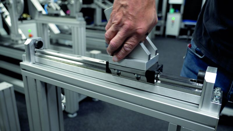 Mit der Profilführungsschiene mit Führungswagen von Norelem lässt sich ein Bauteil in eine bestimmte Richtung bewegen, wobei der schwarze Gummipuffer eventuell auftretende Vibrationen und Stöße absorbiert. (Bild:  Zedler-Institut/Norelem)