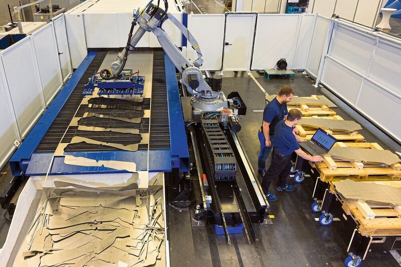 Trumpf hat gemeinsam mit Siemens und weiteren Partnern eine hochautomatisierte Laseranlage für die Blechbearbeitung entwickelt. Im Bild ist die Entnahmestelle zu sehen, bei der zwei Mitarbeiter dabei sind, die Anlage für ihren vollautomatischen Einsatz vorzubereiten.