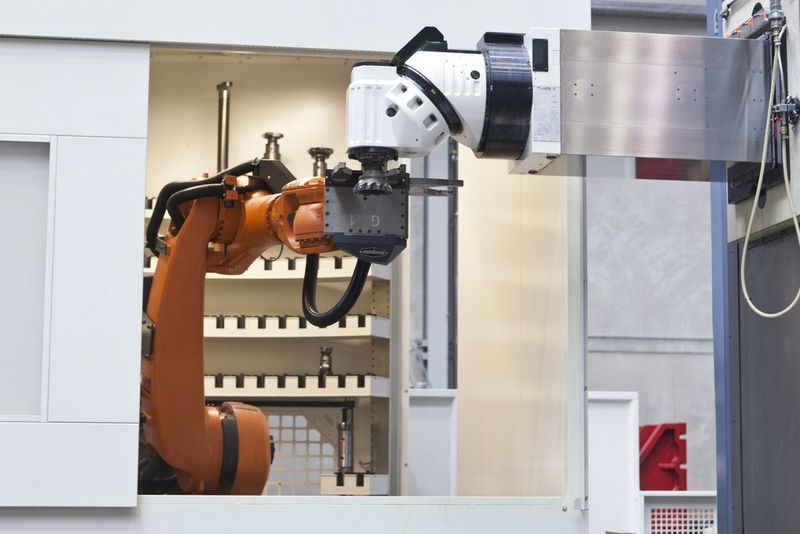Roboter der Werkzeugarena wechselt ein Werkzeug am Universalfräskopf TU 25 C, der eine Indexiergenauigkeit von 0,001° bietet. (Bild: Pama, Springfeld)