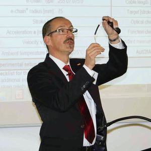 Rainer Rössel, Leiter Geschäftsbereich Chainflex bei Igus, demonstriert bei einem Vortrag, warum an Leitungen in Bewegungen ganz andere Herausforderungen gestellt werden, als dies in fest installierten Bürowelten der Fall ist.