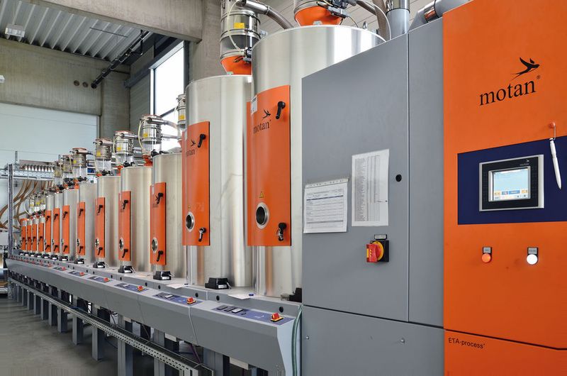 Sicher keine Unglückszahl: 13 Trockentrichter halten die beim Automobilzulieferer FKT üblichen Kunststoffe stets in optimaler Verarbeitungsfähigkeit vor. Eine zentral angeordnete Förderanlage transportiert diese an die Spritzgießmaschinen. (Bild: Motan-Colortronic)