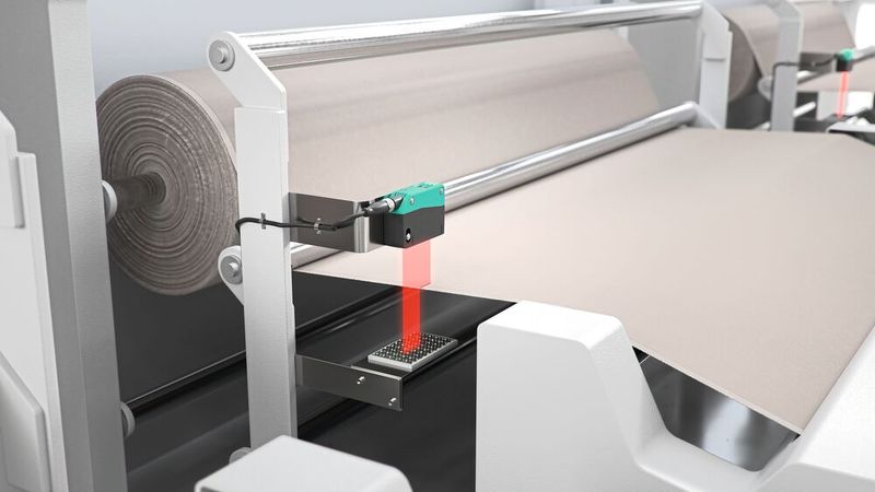 Bahnkantenkontrolle mit R305: Der Sensor meldet kritische Veränderungen im Kantenlauf einer Textilbahn und löst damit die Korrekturroutine aus. (Bild: Pepperl+Fuchs)